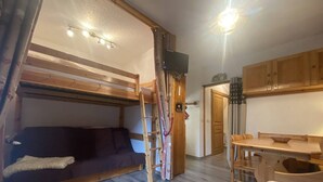 Habitación pequeña con literas, un escritorio, una silla y un televisor.