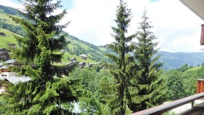 Un balcón con vistas a un paisaje montañoso, casas y árboles.
