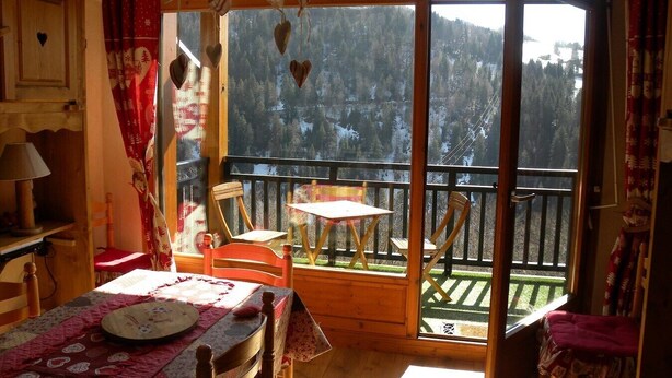 A cozy room with a wooden table, chairs, and a view of a snowy forest through large windows. - P4 Duplex BELLECOMBE area of DIAMOND SPACE (Notre-Dame-De-Bellecombe)