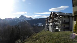 A two-story building with a balcony, set against a mountainous backdrop. - P4 Duplex BELLECOMBE area of DIAMOND SPACE (Notre-Dame-De-Bellecombe)
