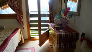 A cozy bedroom with a bed, a dresser, and a window with curtains. - P4 Duplex BELLECOMBE area of DIAMOND SPACE (Notre-Dame-De-Bellecombe)