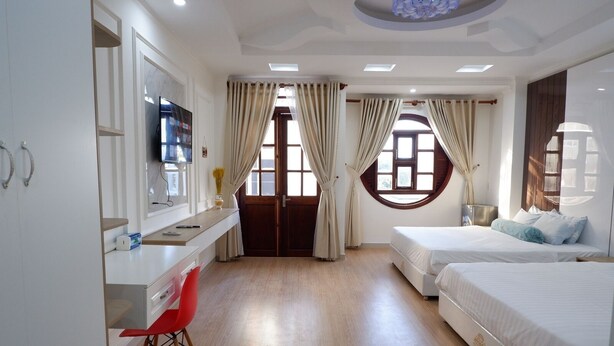 A modern hotel room with a desk, two beds, and a red chair. - Winter Spring Homestay Center (Can Tho)