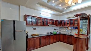 A kitchen with wooden cabinets, a stainless steel refrigerator, and a built-in oven. - Winter Spring Homestay Center (Can Tho)