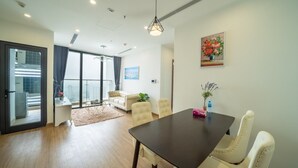 Un salon moderne avec une table en bois foncé, des fauteuils de couleur crème, une grande fenêtre avec des rideaux et un tableau accroché au mur.