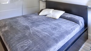 Quarto moderno com uma cama grande, um guarda-roupa branco e uma obra de arte de rosa vermelha na parede.