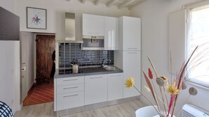 Cozinha moderna com armários brancos, pia de aço inoxidável e painel de azulejos.