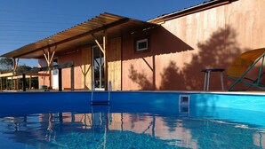 A swimming pool with a wooden deck and a building in the background. - LODGE Palmeira, 6 persons 3 bedrooms, terrace and swimming pool in a quiet area  (Silves)