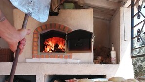A traditional brick oven with a fire burning inside, surrounded by various baked goods on a table. - LODGE Palmeira, 6 persons 3 bedrooms, terrace and swimming pool in a quiet area  (Silves)
