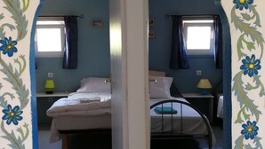 A room with a unique arched doorway, two beds, a small table, and a window with curtains. - LODGE Palmeira, 6 persons 3 bedrooms, terrace and swimming pool in a quiet area  (Silves)