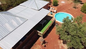 A large building with a metal roof, a swimming pool, and a patio area with outdoor furniture. - LODGE Palmeira, 6 persons 3 bedrooms, terrace and swimming pool in a quiet area  (Silves)