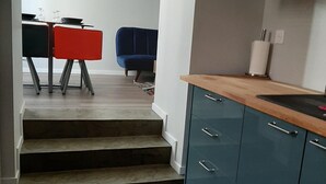 Eine moderne Küche mit blauen Schränken, einer Holzarbeitsplatte und einem Essbereich mit roten und schwarzen Stühlen.