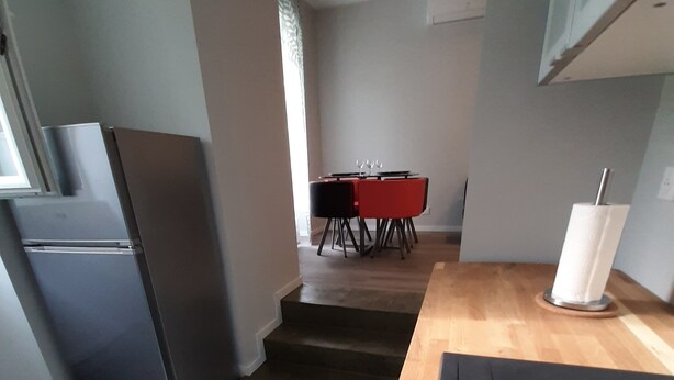 Eine moderne Küche mit einem Edelstahl-Kühlschrank, einer Holz Arbeitsplatte und einem Essbereich mit einem roten Tisch und Stühlen.