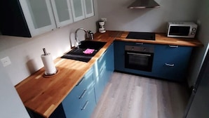 Eine kompakte Küche mit blauen Schränken, einer Holz Arbeitsplatte, einer Mikrowelle und einem Herd.