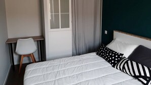 Ein Schlafzimmer mit Bett, Stuhl, einem fensterbepflegten Fenster und einer dunklen Wand.