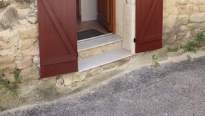 A stone building with a wooden door and steps leading to a kitchen area. - Apartment in a quiet village house (Colonzelle)