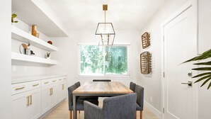 A modern kitchen with white cabinetry, a wooden dining table, and gray chairs. - Bright 3BR · 5 Mi to Disneyland · Sleeps 8, 2 BA (Fullerton)