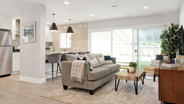 A modern kitchen with a built-in oven and a dining area with a grey sofa and a wooden coffee table. - Bright 3BR · 5 Mi to Disneyland · Sleeps 8, 2 BA (Fullerton)