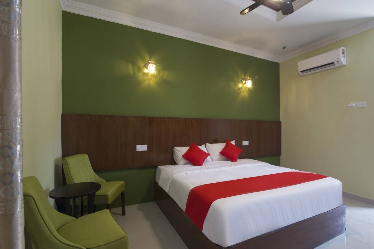 Ein Hotelzimmer mit einem Bett, grünen Stühlen, einem kleinen Tisch und zwei Wandleuchten.