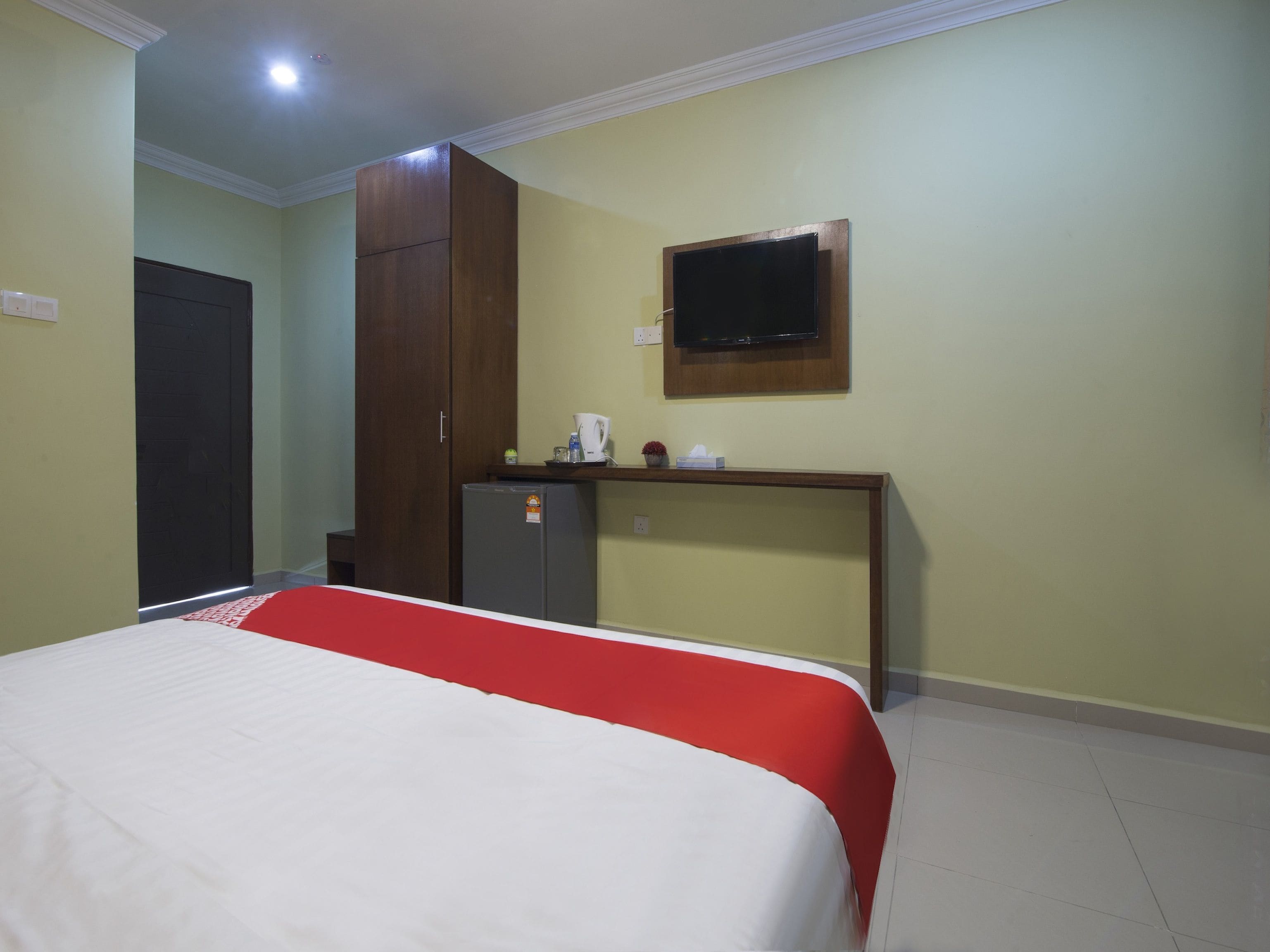 Una habitación de hotel con cama, escritorio, televisor y armario.