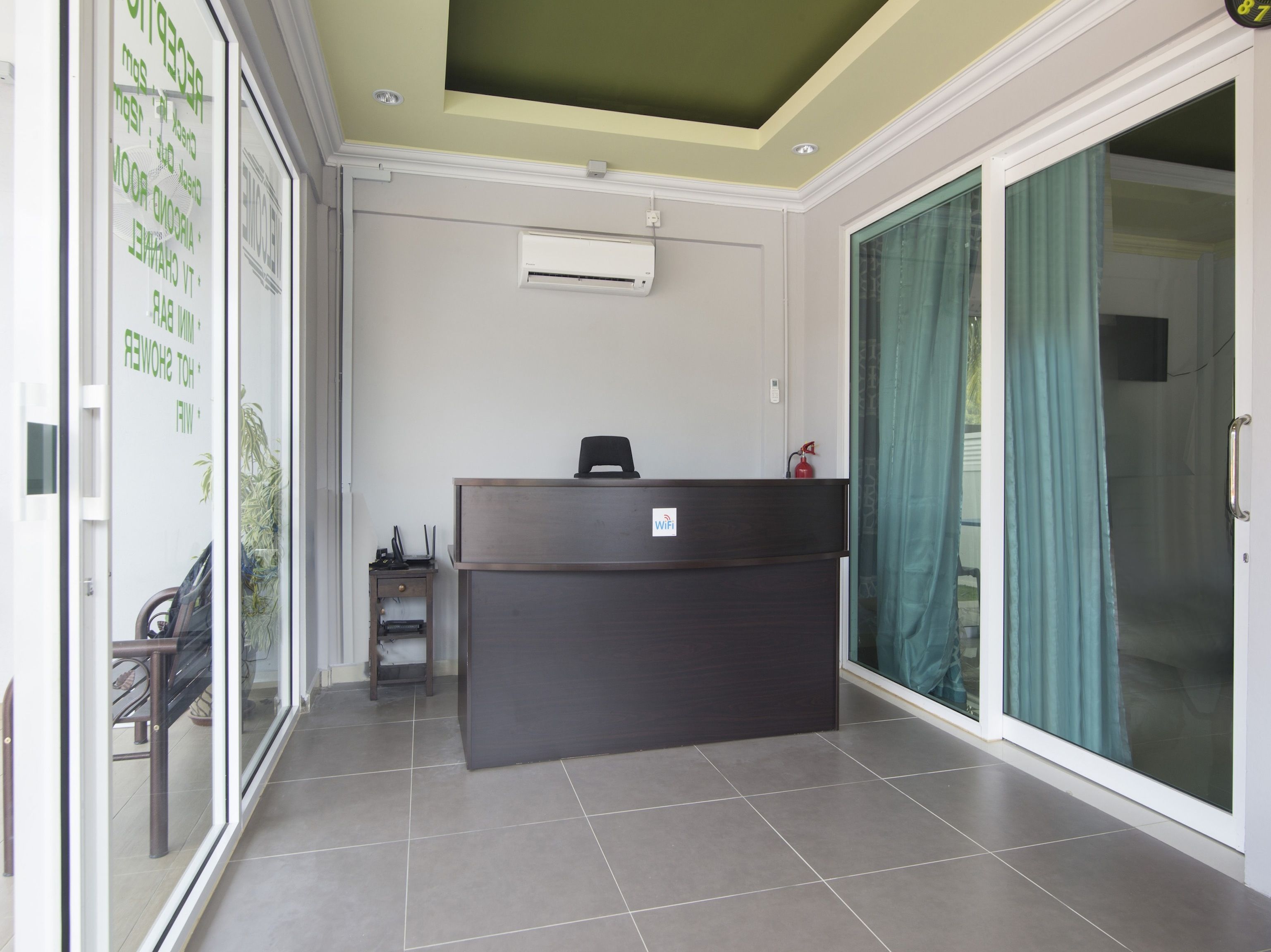 A reception desk with a WiFi sign, a small table with a laptop, and a fire extinguisher.