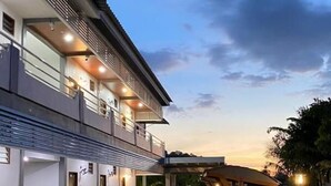A modern multi-story building with a covered outdoor area featuring a patterned tile floor and potted plants. - Norshah Village Resort (Langkawi)