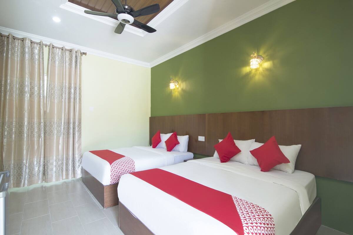 Ein Hotelzimmer mit zwei Betten, einem Deckenventilator und zwei Wandleuchten.