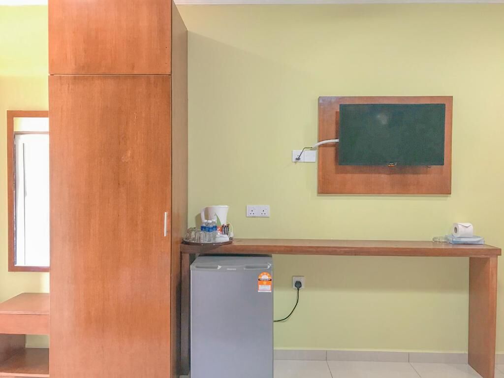 Een kleine kitchenette met een koelkast, een koffiezetapparaat en een magnetron.