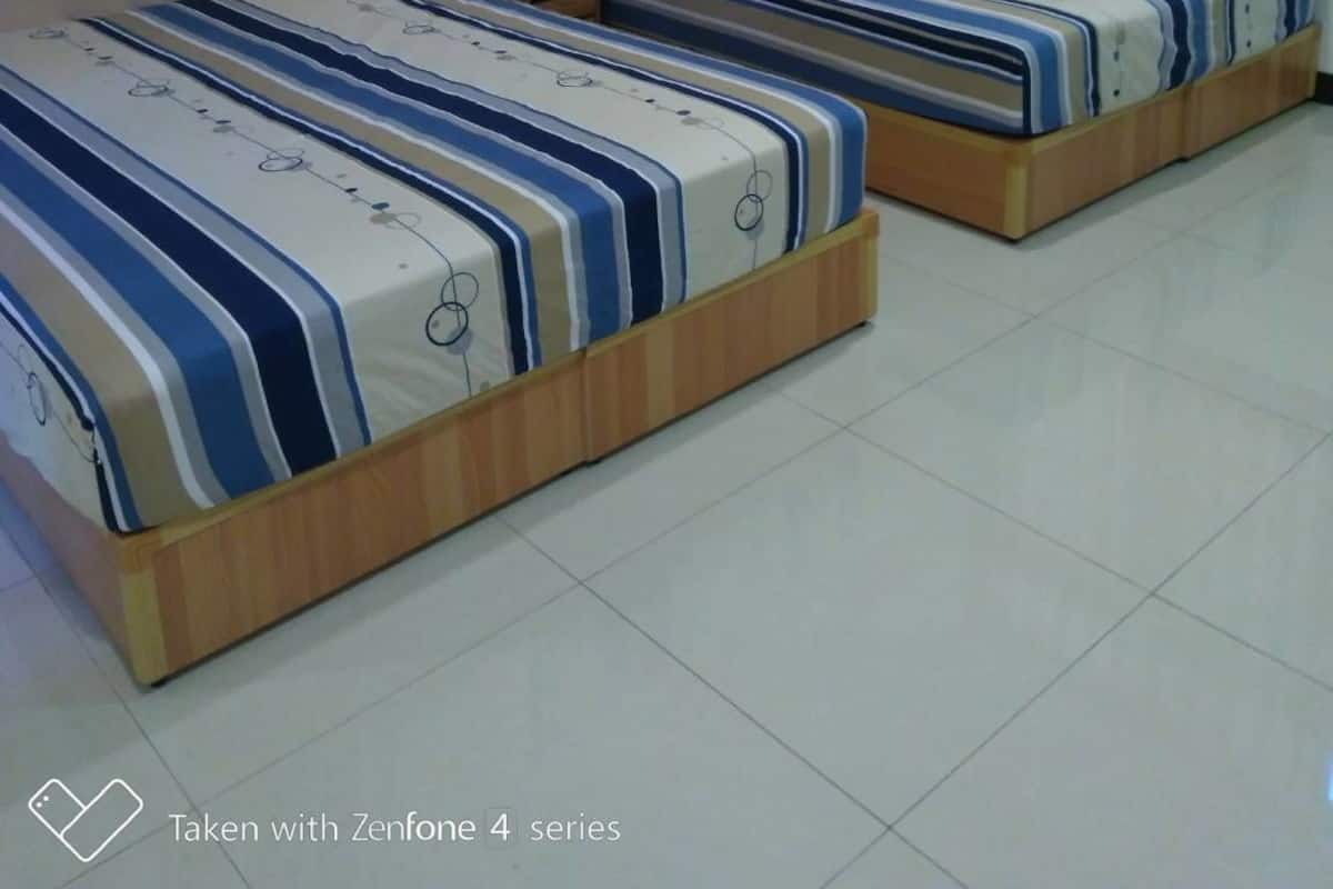 A hotel room with two beds, each with a striped bedspread, a wooden headboard, and a nightstand with a remote control.