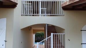 Una escalera con barandas blancas que lleva a un balcón con barandilla metálica.