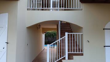 A staircase with white railings leading to a balcony with a metal railing.