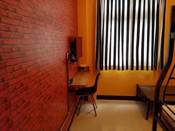A room with a brick wall, a desk with a chair, a window with vertical blinds, and a bed. - Backpack Home 497 No.2 (Jincheng)