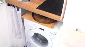 Una cocina compacta con lavadora integrada, un lavamanos y una encimera de madera.