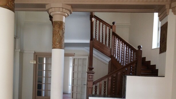 Una escalera con barandillas de madera y un piso con diseño de cuadros.