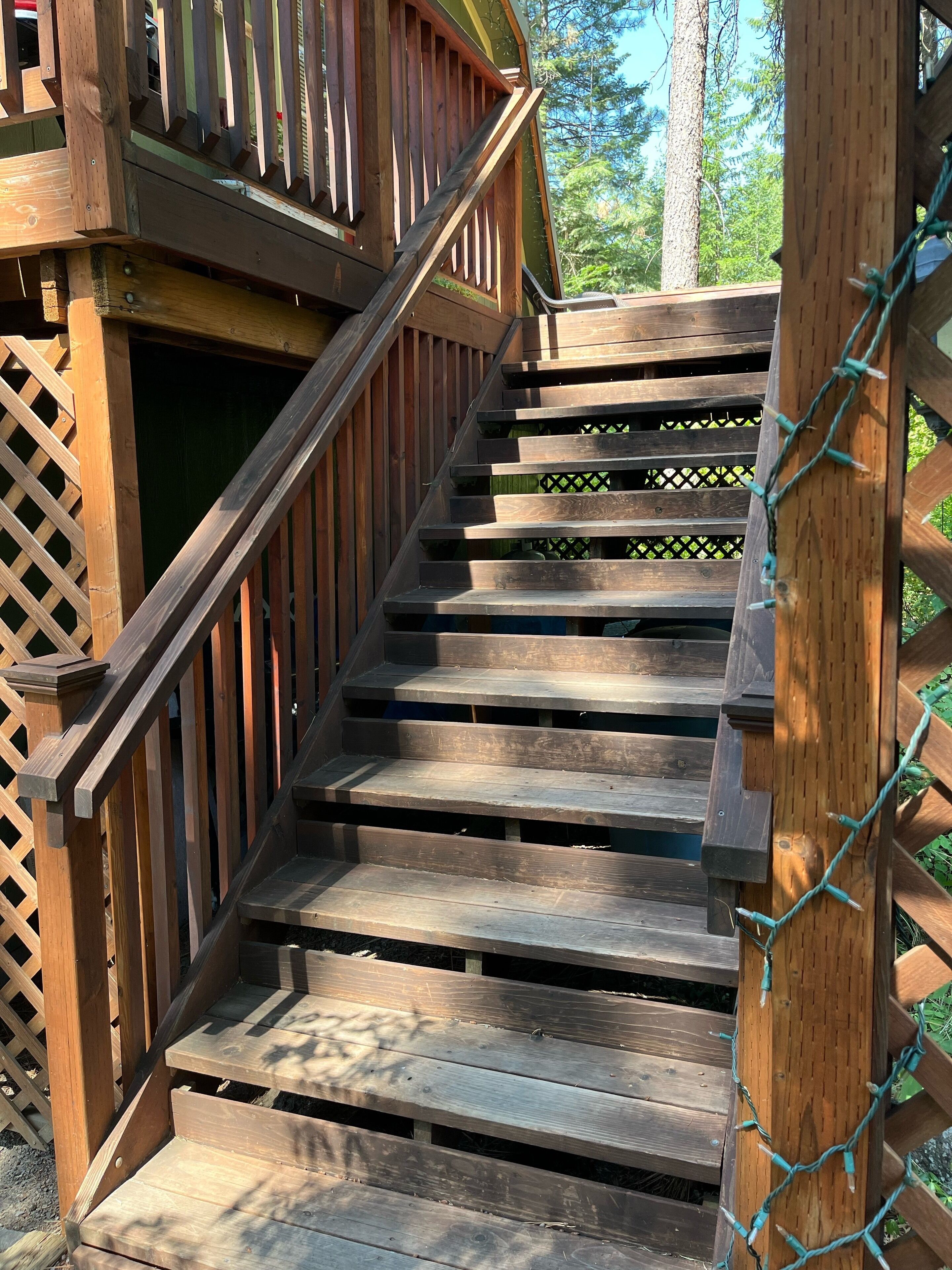 A wooden staircase with a wooden railing, leading to a deck area.