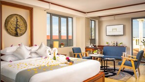 A hotel room with a bed, two chairs, a small table, a TV, and a balcony with a view. - GZ Premier Luxury Residence and Spa (Siem Reap)