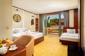 A hotel room with two beds, a dining table with a teapot and fruit, and a balcony with a view of a red-roofed building. - GZ Premier Luxury Residence and Spa (Siem Reap)