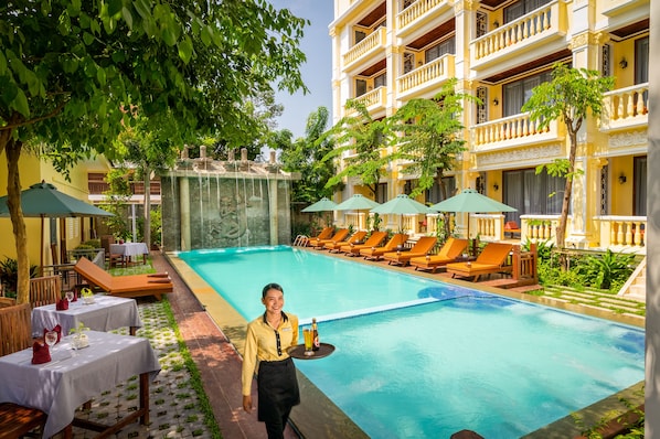 A poolside area with lounge chairs, a waiter, and a dining setup. - GZ Premier Luxury Residence and Spa (Siem Reap)