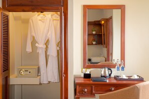 A hotel room with a wooden dresser, a mirror, a robe, a radio, and toiletries. - GZ Premier Luxury Residence and Spa (Siem Reap)