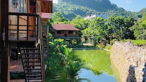 Un bâtiment en bois doté d’un balcon donnant sur un étang et un paysage montagneux.