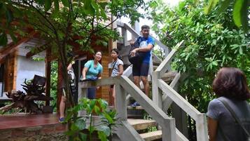 A staircase leading to a wooden deck with a rustic stone wall and a sculpture.