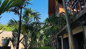 Un jardin tropical avec des palmiers et un bâtiment doté d’un toit rouge.