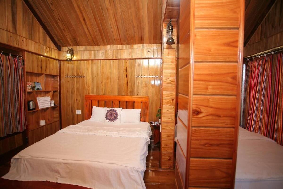 A wooden-paneled room with a bed, shelves, and a hanging light fixture.