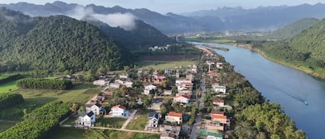 A river running alongside a small village with houses and greenery.
