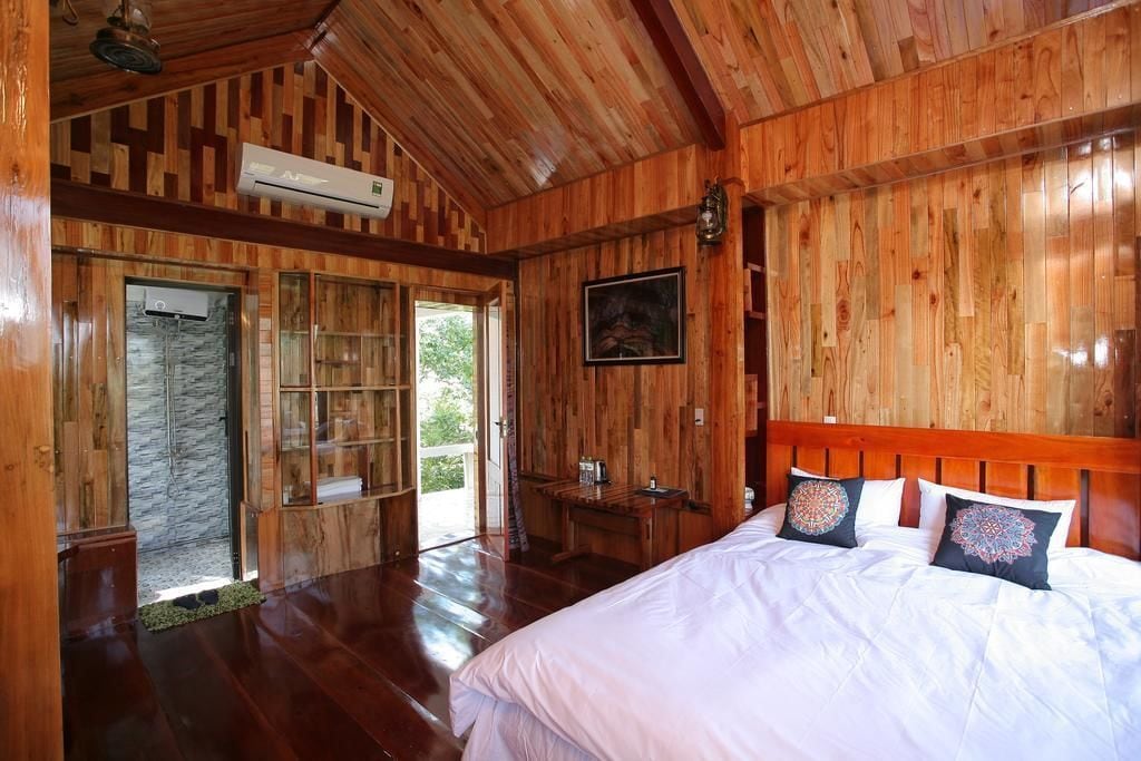 Une pièce en bois avec un lit, une bibliothèque et une porte donnant sur l’extérieur.