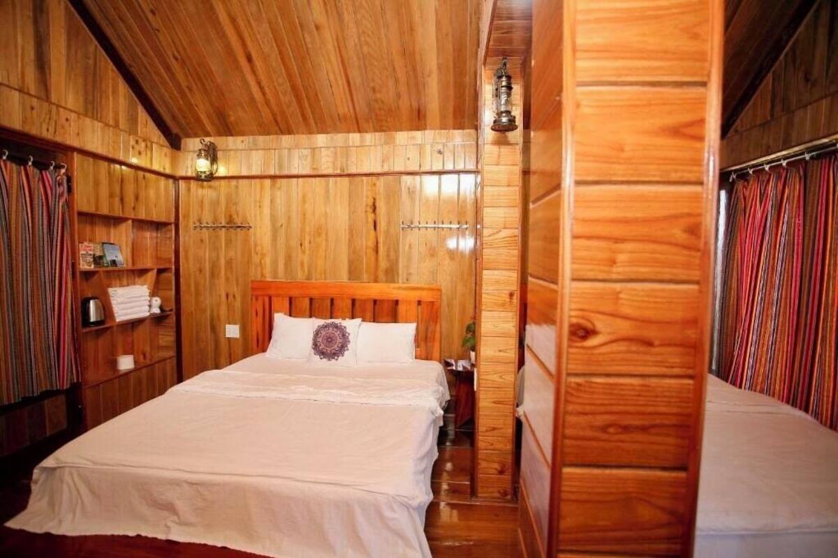 A wooden cabin room with a bed, shelves, and a hanging light fixture.