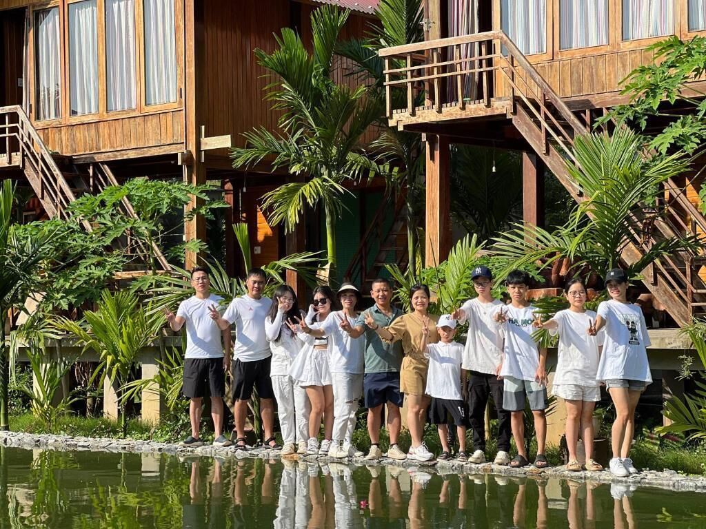 Un grupo de personas junto a una estructura de madera con piscina, rodeado de plantas tropicales.