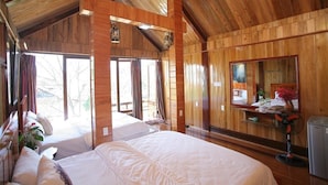 Une cabane en bois avec deux lits, un miroir et une petite table sur laquelle se trouve un ventilateur.