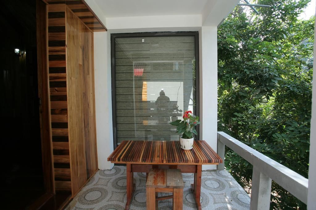 A wooden table with a bench on a balcony with a patterned floor, a potted plant, and a view of greenery.
