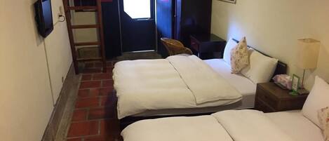 A hotel room with two beds, a desk, a chair, a TV, and a ladder leading to a door.