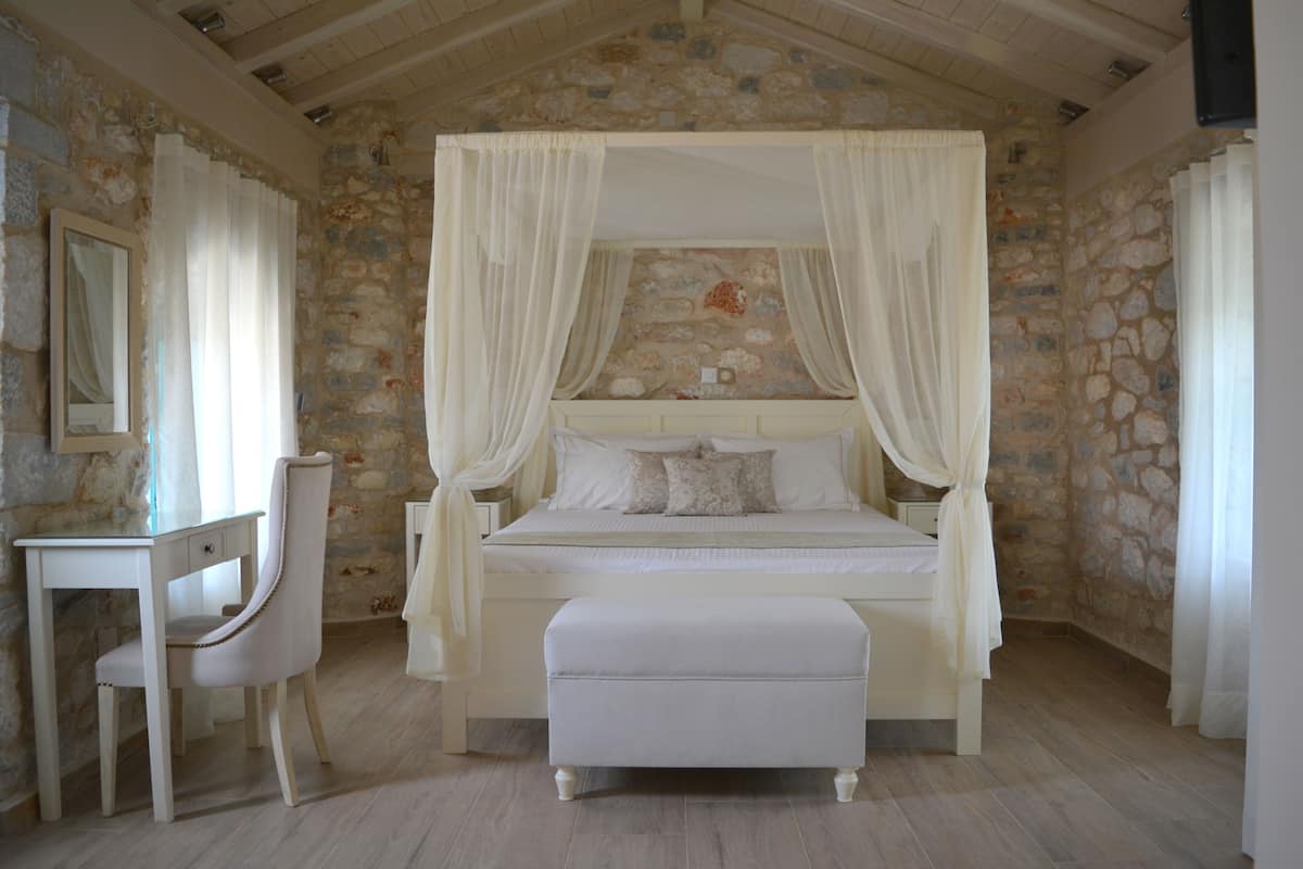 Ein Schlafzimmer mit Steinwand, einem Himmelbett, einem Nachttisch und einem Sessel.
